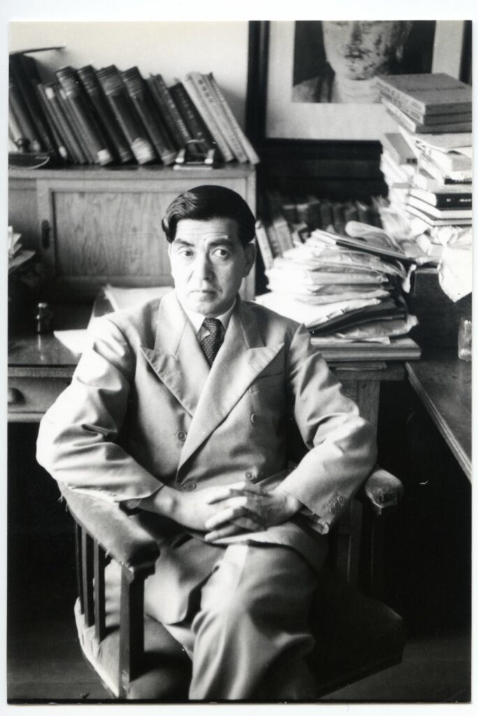 Taniguchi Yoshiro, founder of Meiji Mura, sits in his work chair surrounded by books and papers.