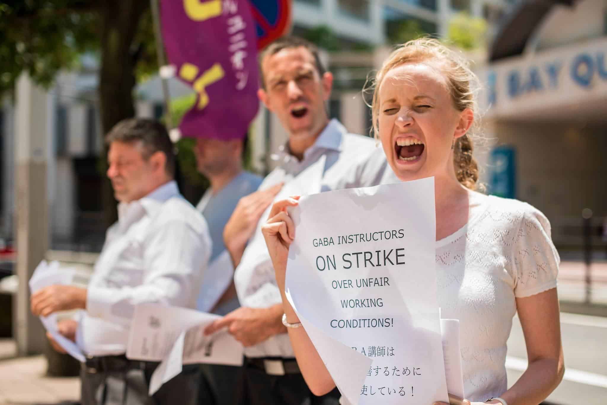 Protesters on strike against English teaching company Gaba in Japan hold placards in English and Japanese.