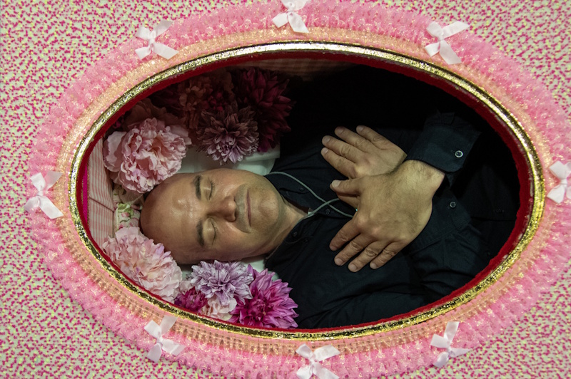 Author lying in a coffin with his hands folded over his chest. 