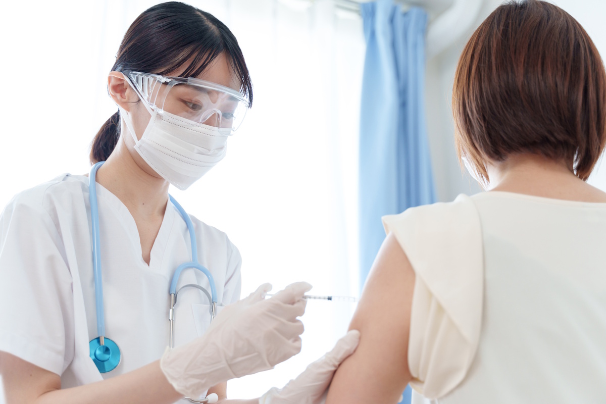 Female medical professional giving a woman a shot in the left arm